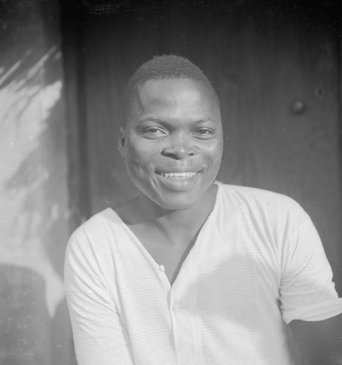 Igbo man smiling, wearing a white collarless shirt