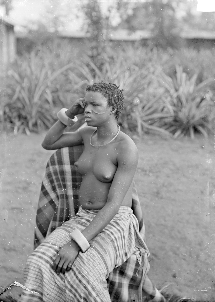 A photograph depicting a seated woman with abdominal scarification and ivory bangles.