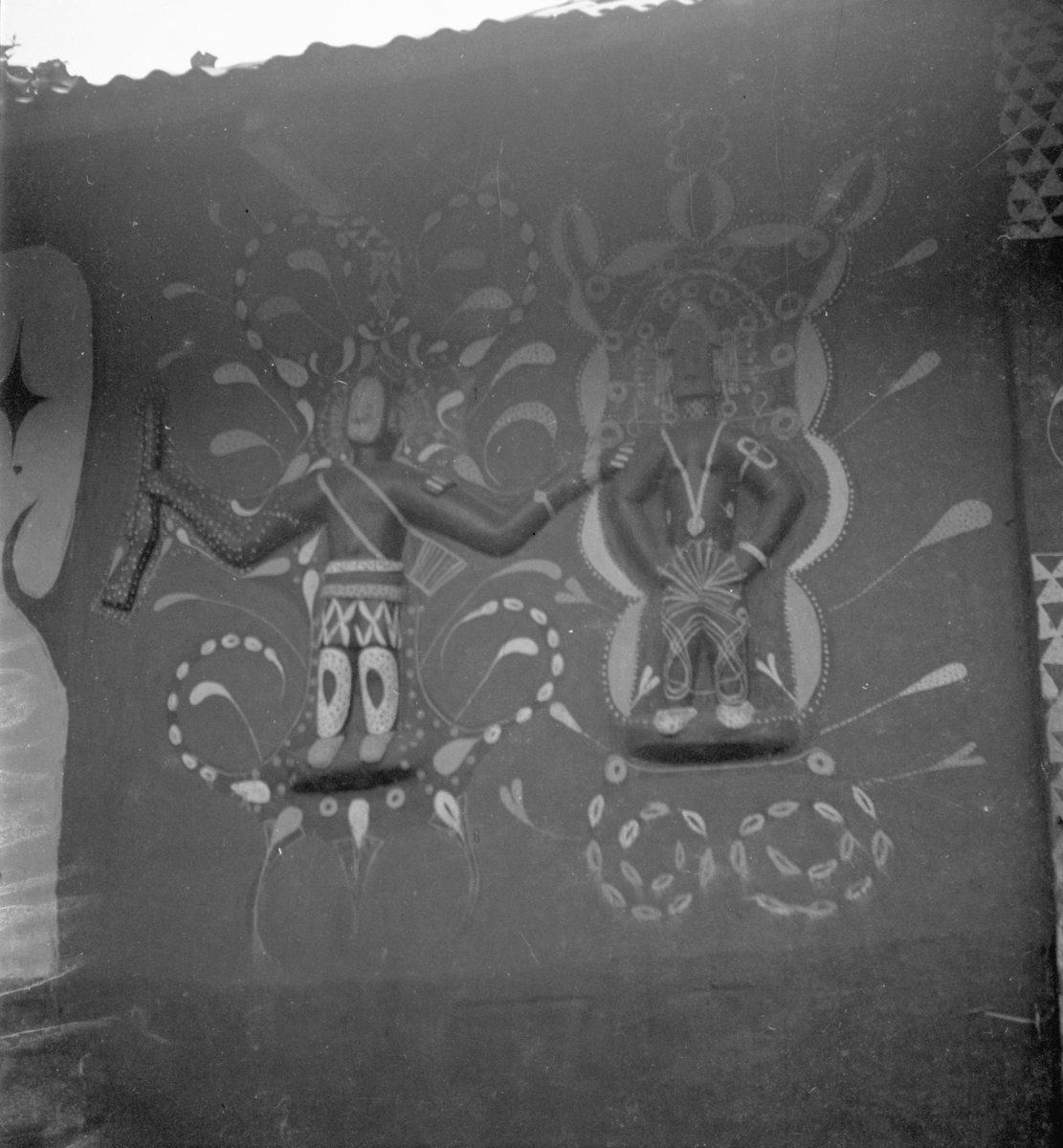 A photograph of mural decorations in Nri Akwa showing two stylized figures in relief.