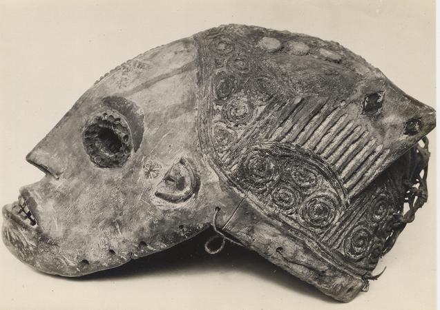 Profile view of an Agbhogho Mmanwu maiden mask with elaborate spiral carvings on the headgear.