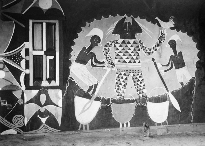 Monochromatic mural on a courthouse wall in Nri featuring stylized humanoid figures and geometric patterns.